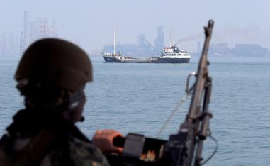 US Navy soldier stands guard as an oil tanker sails past.
