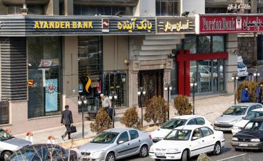 Iranians walk past a Bank Ayandeh and Parian, on the first anniversary of the nuclear agreement, in the capital Tehran on Jaunary 14, 2017.