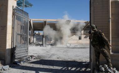 A member of the U.S.-backed Syrian Democratic Forces SDF throws a bomb to check for more explosives as they clear the stadium that was the site of Islamic State fighters' last stand in the city of Raqqa, Syria.