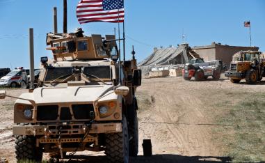 A US soldier, left, sits on an armored vehicle in Manbij, northern Syria.