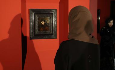 زائرة تتطلع للوحة 'رأس شاب' بعيد عرضها في لوفر أبوظبي