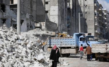A tractor and trucks remove the rubble from buildings that were heavily damaged or destroyed during battles between rebel fighters and regime forces, in the former opposition held district of Salaheddin in the northern Syrian city of Aleppo on February 11, 2019.
