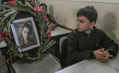 طفل فلسطيني ينظر إلى صورة زميله الشهيد في مدرسة في غزة
