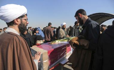 People mourn over a flag-draped coffin of a member of Iran's Revolutionary Guard who was killed in a suicide car bombing that struck a bus carrying the Guard troops, killing at least 27 people on Wednesday, upon arrival of the victims bodies and wounded troops at an airport in Isfahan, Thursday, Feb. 14, 2019.