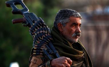 A Syrian Democratic Forces (SDF) fighter holds a machine gun on his shoulder as he attends the funeral of a slain People's Protection Units (YPG) commander in the northeastern city of Qamishli on December 6, 2018.