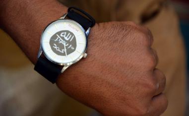 A member of the Iraqi special forces puts on a watch belonging to a former Islamic State (IS) group fighter, bearing the group's logo, found by security forces in the Old City of Mosul, in the city's western industrial district on June 29, 2017.