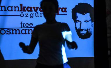 A woman passes in front of a screen featuring jailed businessman and philanthropist Osman Kavala during a press conference of his lawyers on October 31, 2018.