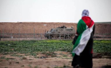 امرأة فلسطينية أمام عربة مدرعة إسرائيلية على الحدود بين إسرائيل وغزة