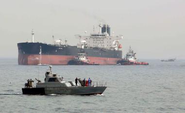 An Iranian military speedboat patrols the waters as a tanker prepares to dock at the oil facility in the Khark Island, Iran