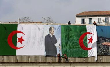 Algerian city employees install national flags and a poster of President Abdelaziz Bouteflika on a street in Algiers.