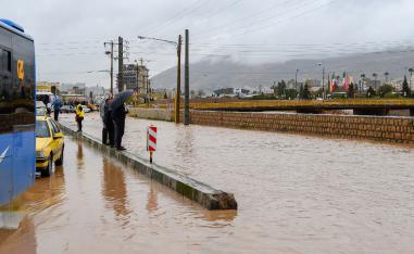 People stand near a flooded street after a flash flooding in Shiraz, Iran, March 26, 2019.