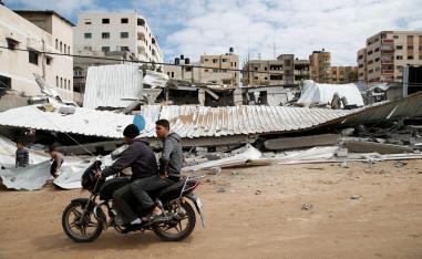 فلسطينيان يمران على دراجة بالقرب من مبنى دمرته اسرائيل بقصف جوي على غزة 