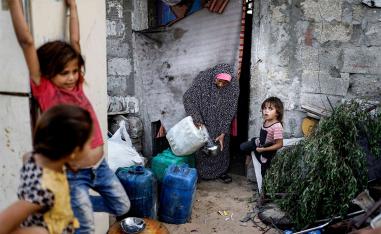 A Palestinian woman cleans a teapot with tap water drawn from a cistern in a poor neighbourhood in Khan Yunis