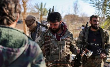 Syrian Democratic Forces (SDF) stand at a makeshift camp for IS group members and their families in Baghouz