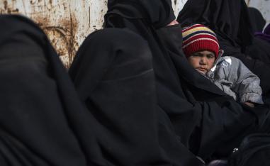 In this file photo taken on February 14, 2019 women and children who fled the Islamic State (IS) group's embattled holdout of Baghouz sit waiting in the back of a truck in the eastern Syrian province of Deir Ezzor.