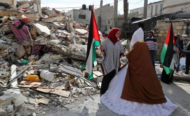 عروس فلسطينية تمر أمام بيتها الذي دمرته غارة إسرائيلية على غزة