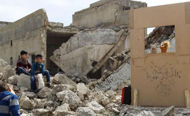 Children watch a puppet show performed by a Syrian actor, through a makeshift puppet theatre set up among the rubble of collapsed buildings in the town of Saraqib.