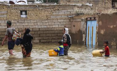 An Iranian family walks through a flooded street in a village around the city of Ahvaz