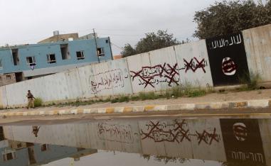 A Shiite fighter from the Popular Mobilisation units walks down an alley bearing defaced Islamist slogans and emblems in Tikrit on April 1, 2015.