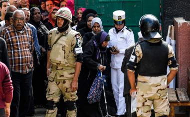 An Egyptian policewoman helps an elderly voter as she arrives at a polling station