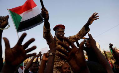 A Sudanese soldier sits on the shoulders of a protester in Khartoum