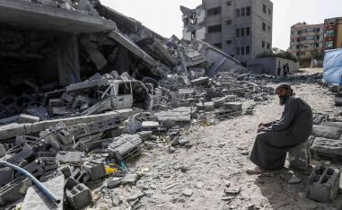 فلسطيني يجلس أمام مبنى دمرته غارات إسرائيلية في غزة