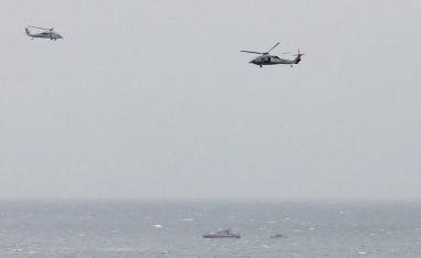 Iranian Revolutionary Guard boat is seen near the U.S. aircraft carrier USS George H. W. Bush in the Strait of Hormuz as U.S. Navy helicopters hover nearby