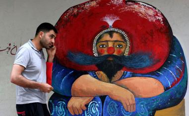 إيراني يمر بجانب تخطيط على حائط وسط طهران