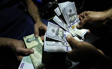 تجار عملة يتبادلون الدولار والتومان الإيراني