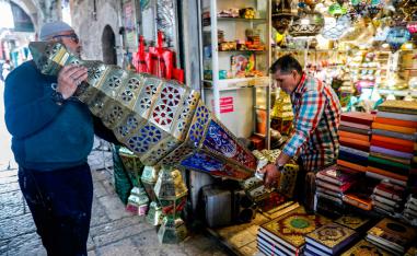 Palestinian craftsman Issam Zughair (R) helps an elderly man transport a large Ramadan lantern