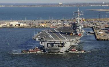 2013 file picture shows tug boats assisting the Nimitz-class aircraft carrier USS Dwight D. Eisenhower (CVN 69) as it pulls away from the pier at Naval Station Norfolk, Virginia