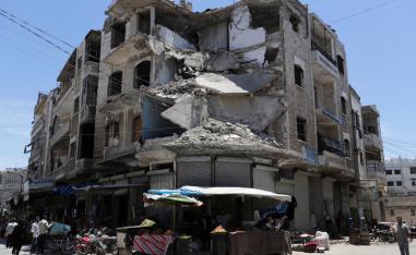People walk past a damaged building in the city of Idlib