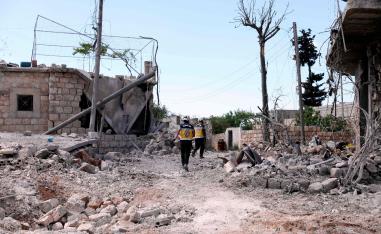 Members of the Syrian Civil Defence, also known as the White Helmets, walk amidst the debris of homes following bombardment by regime forces on the village of Ibdita on May 4, 2019