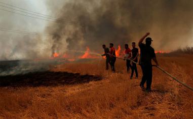 Iraqi farmers and other residents attempt to put out a fire that engulfed a wheat field in the northern town of Bashiqa