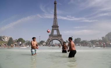 شباب يلعبون في نافورة أمام برج إيفل في باريس خلال موجة الحر في  يونيو 2019