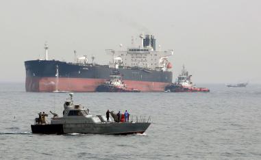 Iranian military speedboat patrols the waters as a tanker prepares to dock