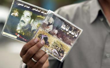 An Iraqi street vendor holds video compact discs titled "crimes of the dictator Saddam Hussein" in Kurdish