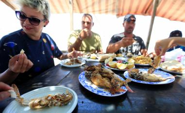 Jina Talj, an environmentalist, eats fried lionfish in Sarafand, Lebanon