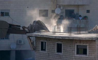 Palestinian family watching Israeli security forces tearing down one of the Palestinian buildings 