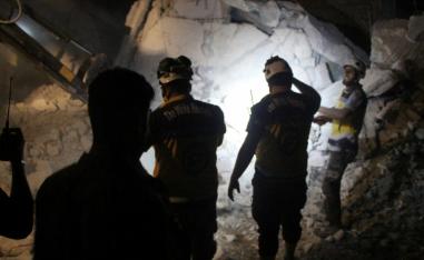 Syria Civil Defence (White Helmets) members search the rubble of a damaged building for victims