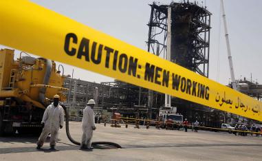 Workers work in front of the recent attack Aramco's oil processing facility in Khurais