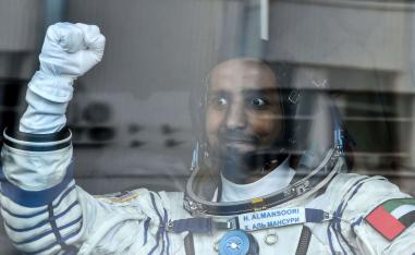 United Arab Emirates' astronaut Hazza Al Mansouri raises his fist from a bus before boarding a Soyuz rocket to the International Space Station