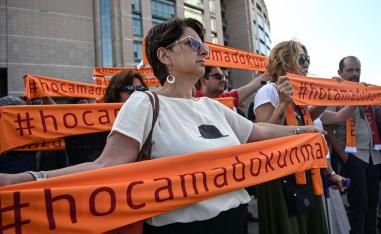 People hold scarf banners reading " Do not touch my teacher " during a demonstration outside of Istanbul's courthouse