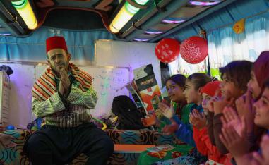 Displaced Syrian children sing on a bus converted into a classroom near the village of Hazano in northwestern Syria