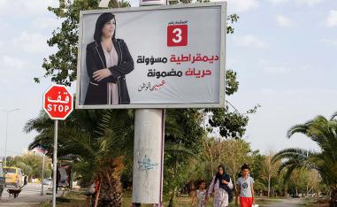 People walk past an election campaign billboard depicting presidential candidate, Abir Moussi, in Tunis