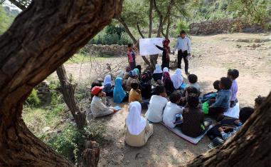 School children attend an open-air class under a tree near their unfinished school in the southwestern Yemeni village of al-Kashar