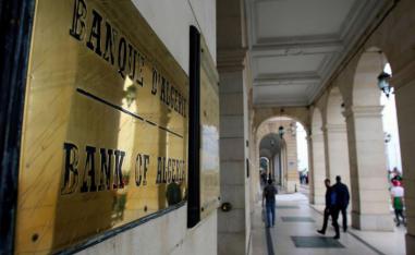 People walk past the headquarters of the Bank of Algeria in Algiers