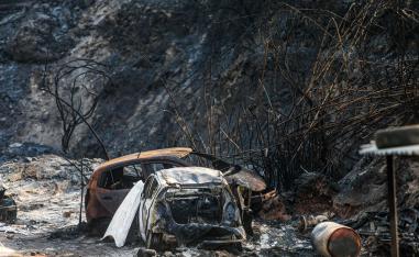 Vehicles lying on the side of a road, after they were burnt by fires near the town of Damour in Lebanon's Chouf mountains