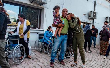 People react as the body of a man killed during Turkish shelling in the area surrounding the Syrian Kurdish town of Ras al-Ain arrives at a hospital in the nearby town of Tal Tamr