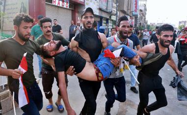 An injured protester is carried after reacting to tear gas fired by security forces during a protest in Tahrir Square